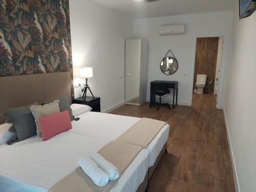 a bedroom with a large white bed and a desk at Hostal GARDEN ROUS in Paiporta