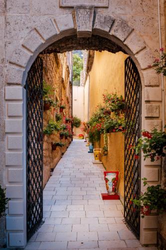 an alleyway with potted plants and an archway with flowers at Heritage Grand Perast By Rixos in Perast