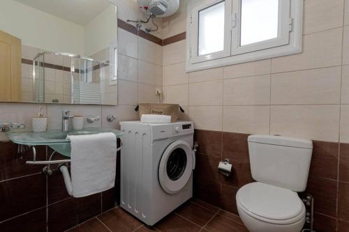 een badkamer met een wasmachine en een wastafel bij Dimitra's South House in Neochorákion