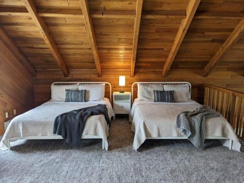 two beds in a room with wooden ceilings at Base Camp in Cortland