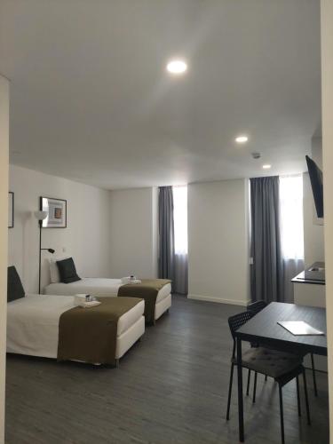 a hotel room with two beds and a table at OH Studios Lousã in Lousã