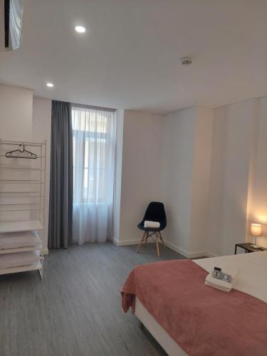 a bedroom with a bed and a chair and a window at OH Studios Lousã in Lousã