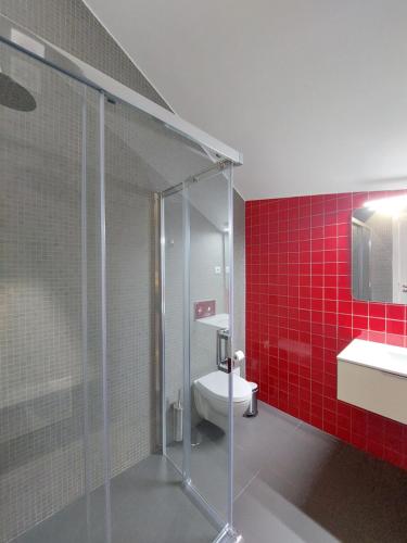 y baño con ducha, aseo y azulejos rojos. en OH Studios Lousã, en Lousã