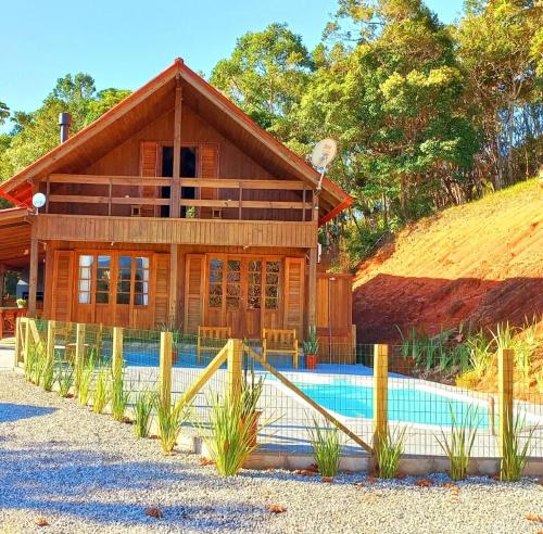 una casa con piscina frente a ella en Recanto Paraíso da Colina, en Santo Amaro da Imperatriz