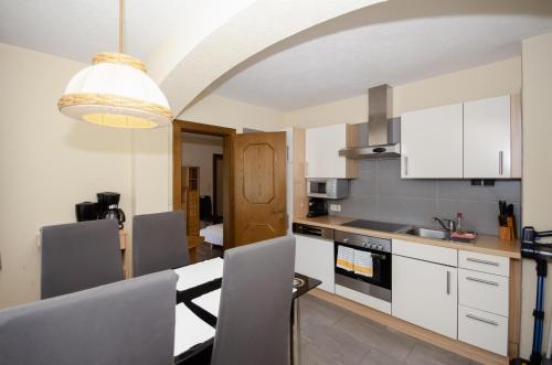 a kitchen with white cabinets and a table and chairs at Familienhotel Steindl in Millstatt