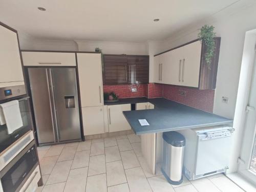 a kitchen with white cabinets and a blue counter top at Cosy 3-Bed house in Clydach - TV in every bedroom! in Clydach