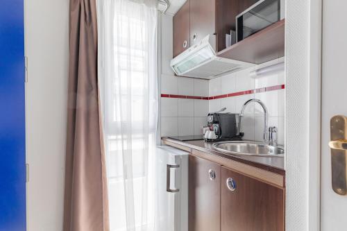 una pequeña cocina con fregadero y ventana en Appart'City Confort Pau Centre en Pau
