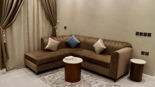 een woonkamer met een bruine bank en 2 tafels bij شقق فاتوران الفاخره in Al Madinah
