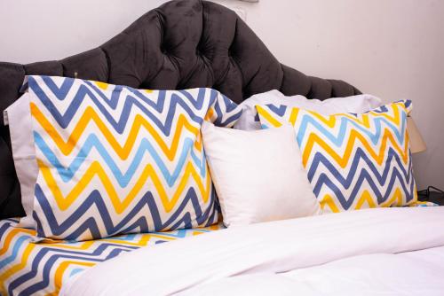 una cama con almohadas coloridas encima en Appartement Cosy 3 bonapriso en Duala