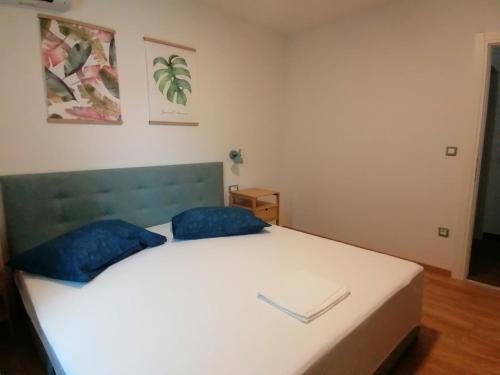 a bedroom with a white bed with blue pillows at Apartmani Mares - 20 m from the beach in Brela