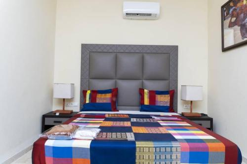ein Schlafzimmer mit einem farbenfrohen Bett mit zwei Lampen in der Unterkunft Hôtel Bachou in Dakar