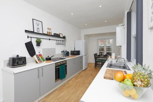 a kitchen with white cabinets and a bowl of fruit on a counter at Timeless Elegance 4-Bed Victorian Charm in Leicester