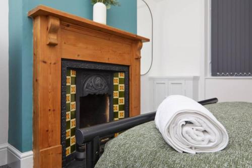 a blanket laying on a bed next to a fireplace at Timeless Elegance 4-Bed Victorian Charm in Leicester