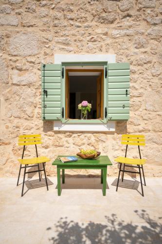 a table with two chairs and a window with a bowl of fruit at BRAND NEW Stone house MARCELA, 3 double bedrooms, pool in Lun