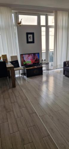 uma sala de estar com televisão e piso em madeira em Hollywood Apartament Piotrkowska Klimat,Jakość,Styl em Lódź