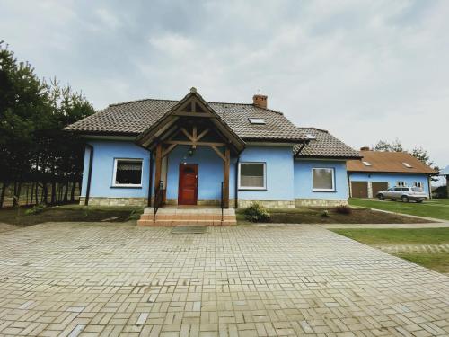 una casa azul con una puerta roja en una entrada en Agroturystyka Włochate Ranczo 