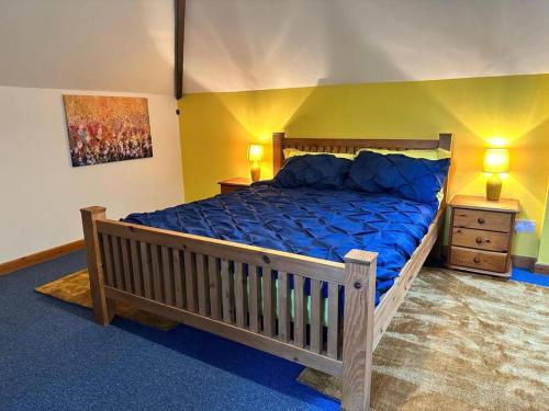 a bedroom with a large bed with a blue comforter at Stable Cottage in Germansweek