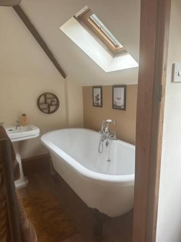 a bathroom with a large white tub and a sink at Stable Cottage in Germansweek