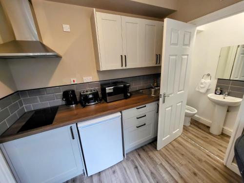 eine kleine Küche mit weißen Schränken und einem Waschbecken in der Unterkunft Stay Sleep Rest - NG2 in Nottingham