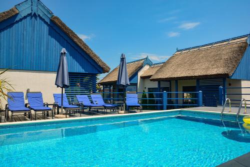 a swimming pool with chairs and umbrellas next to a house at Déjà Blue - ADULT ONLY in Sfântu Gheorghe