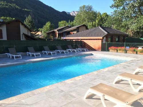 a swimming pool with chairs and a house at Les Granges de Leo in Aston