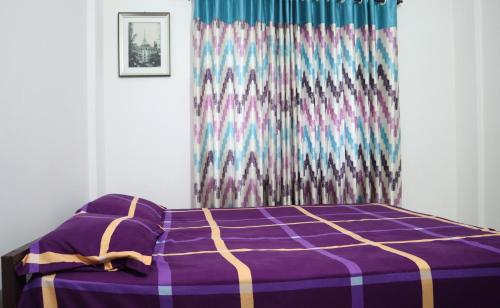 1 dormitorio con cama morada y cortina en Green Apartments - AC 1 BHK Apartments in Cheruthuruthi, Thrissur, en Cheruthuruthi