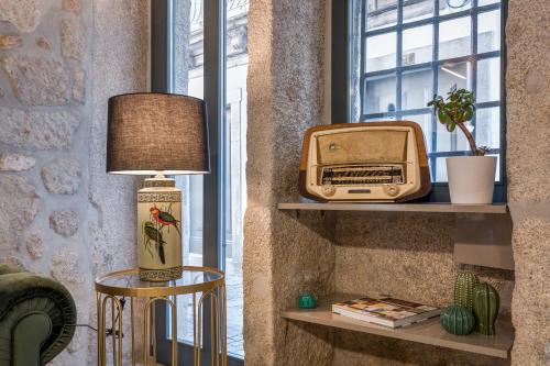 Zimmer mit einem TV und einem alten Radio auf Regalen in der Unterkunft Ribeira Douro Hotel in Porto