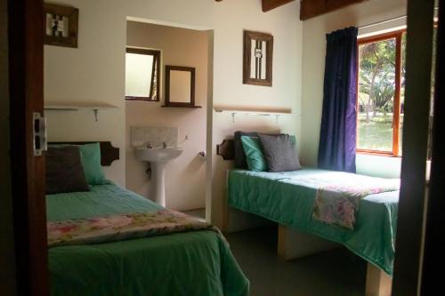 a bedroom with two beds and a sink and a window at Whistling Woods in Empangeni