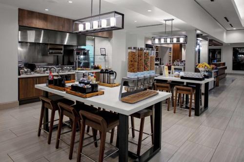 Una cocina con un mostrador con sillas y mesas. en Hilton Garden Inn Atlanta Perimeter Center, en Atlanta