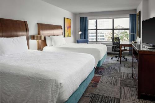 a hotel room with two beds and a desk at Hilton Garden Inn Atlanta Perimeter Center in Atlanta