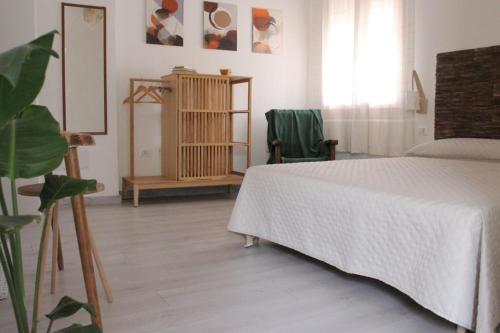 - une chambre avec un lit blanc, une table et une plante dans l'établissement Giobo Rooms, à Siniscola