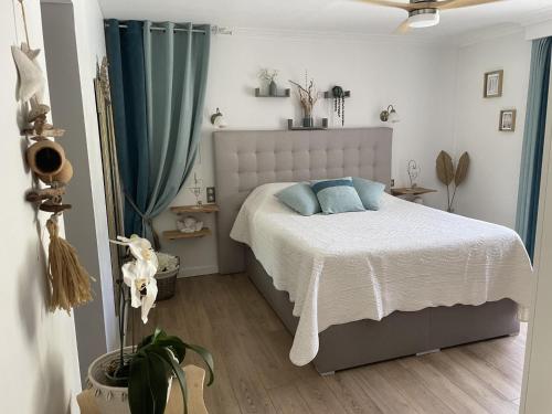 une chambre avec un lit blanc avec des oreillers bleus dans l'établissement le Gabron, à Puget-sur Argens