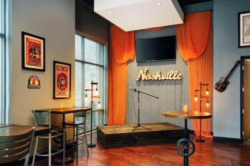a room with two tables and a stage with a television at Hilton Garden Inn Nashville Downtown Convention Center in Nashville