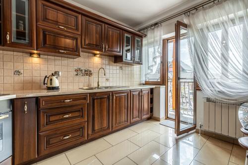 a kitchen with wooden cabinets and a large window at Apartament Dana in Poronin