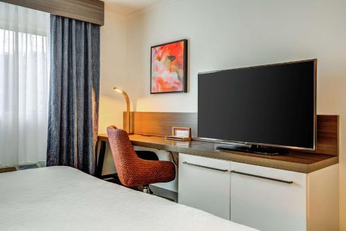 a hotel room with a desk with a flat screen tv at Hilton Garden Inn Boston Waltham in Waltham