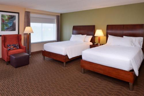 a hotel room with two beds and a chair at Hilton Garden Inn White Marsh in White Marsh