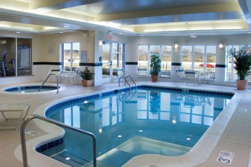 einen Pool in einer Hotellobby mit Stühlen und Tischen in der Unterkunft Hilton Garden Inn Akron-Canton Airport in North Canton