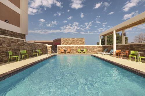 a swimming pool with green chairs and a building at Home2 Suites by Hilton College Station in College Station
