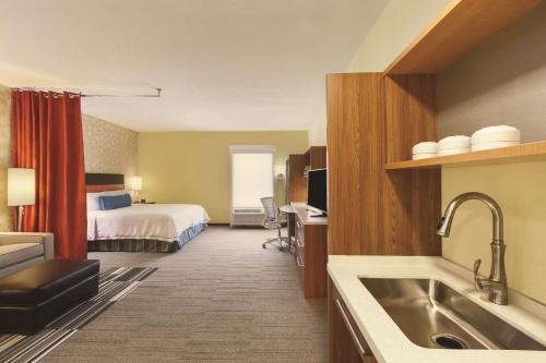 カレッジ・ステーションにあるHome2 Suites by Hilton College Stationのベッドとキッチン付きの広いホテルルームです。