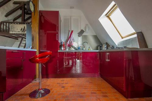 une cuisine avec des placards rouges et un tabouret rouge dans l'établissement Appartement de caractère au cœur du vieux Tours, à Tours
