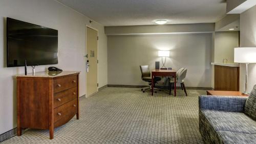 a living room with a couch and a tv and a table at Embassy Suites Cincinnati - RiverCenter in Covington