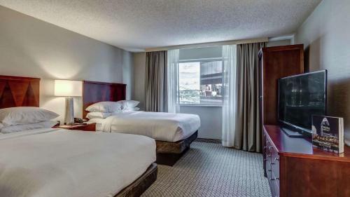 a hotel room with two beds and a flat screen tv at Embassy Suites Cincinnati - RiverCenter in Covington
