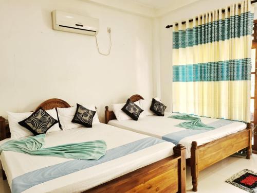 two twin beds in a room with a window at Thuruliya Residence in Sigiriya