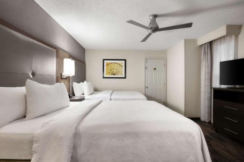 a hotel room with two beds and a ceiling fan at Homewood Suites Dallas-Addison in Addison