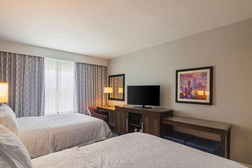 a hotel room with two beds and a desk with a television at Hampton Inn & Suites-Dallas/Richardson in Richardson