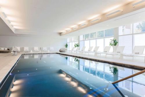 - une grande piscine avec des chaises blanches dans un bâtiment dans l'établissement Hampton Inn & Suites Dallas Downtown, à Dallas