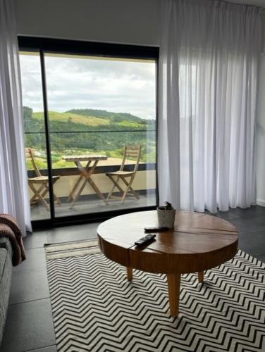 a living room with a table and a balcony at FURNAS DREAM HOUSE in Furnas