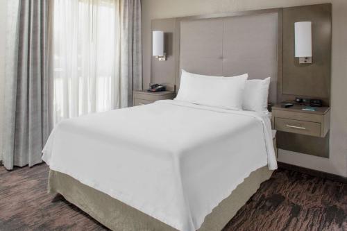 a large white bed in a hotel room with a window at Homewood Suites by Hilton Dallas-Irving-Las Colinas in Irving