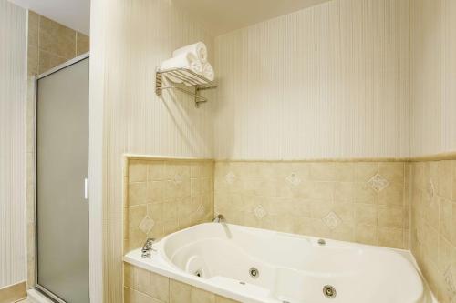 La salle de bains est pourvue d'une baignoire blanche et d'une douche. dans l'établissement Hilton Garden Inn Dallas Lewisville, à Lewisville