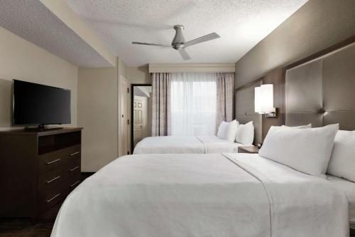a hotel room with two beds and a flat screen tv at Homewood Suites by Hilton Dallas-Plano in Plano